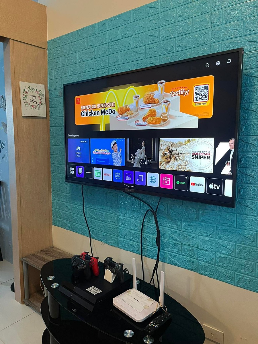 Wall-mounted smart TV with streaming apps and PS4 controllers