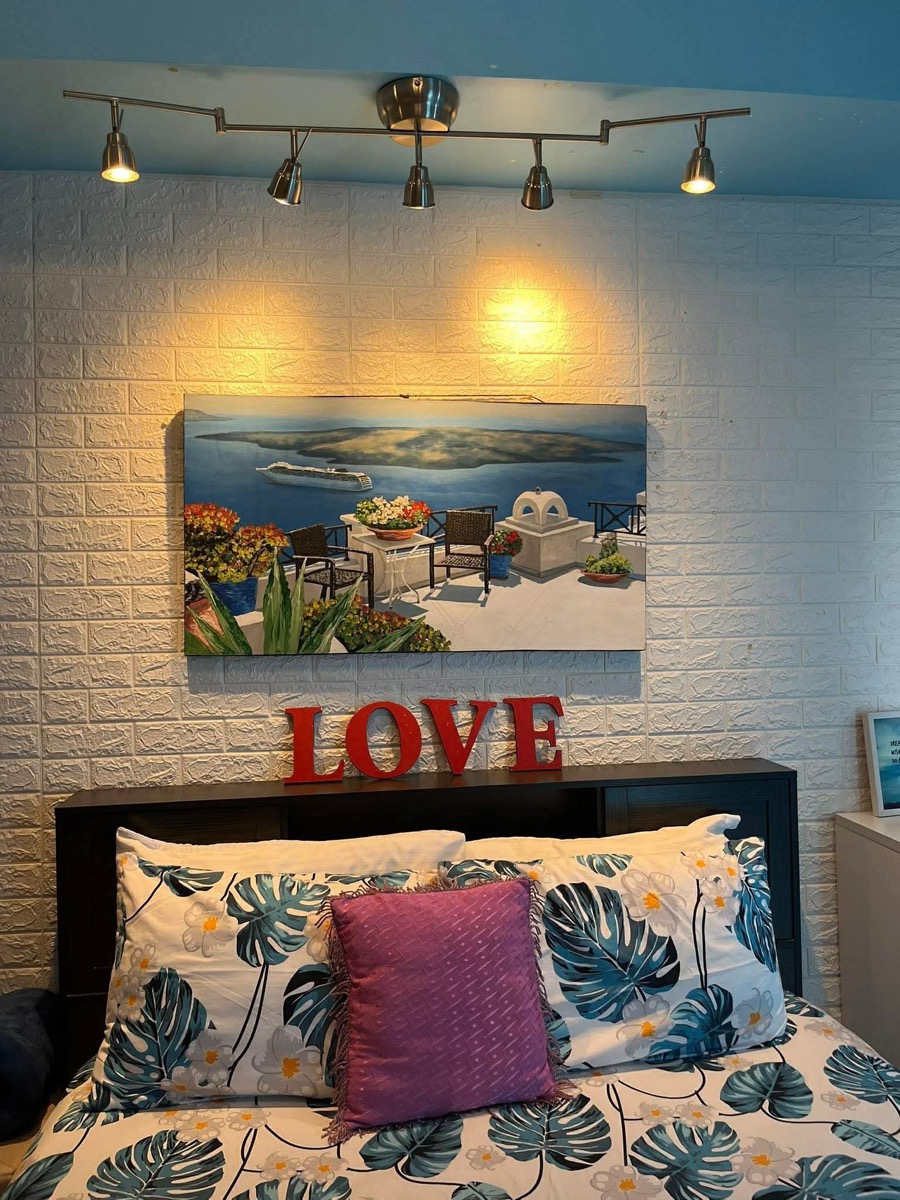 Queen bed with Santorini artwork and LOVE sign above the headboard